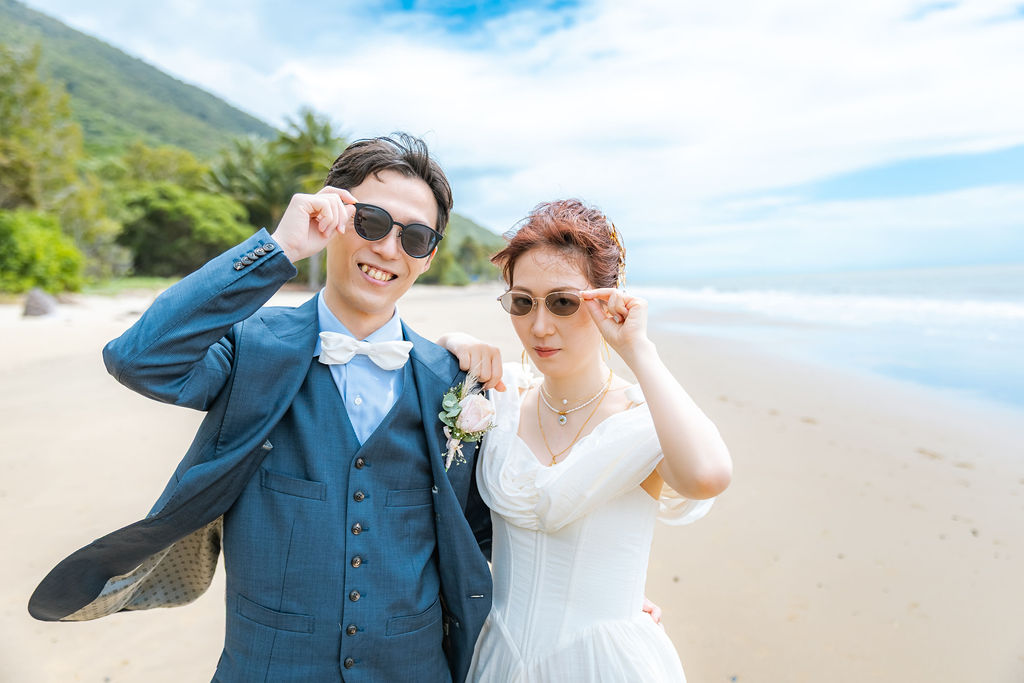 サングラスをかけて笑い合うビーチの新郎新婦