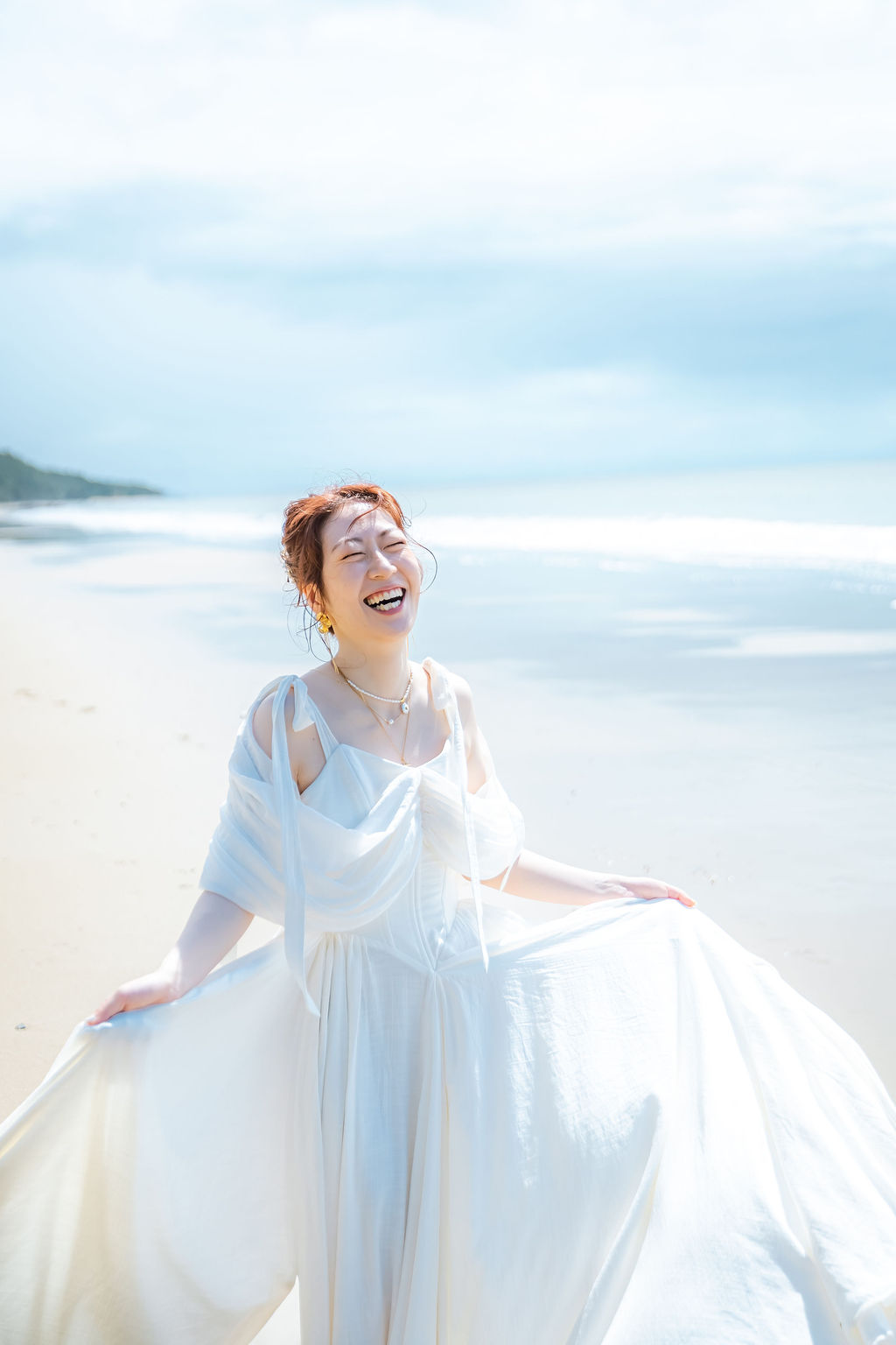 ドレスの裾を持ち上げて笑う花嫁の縦長ポートレート