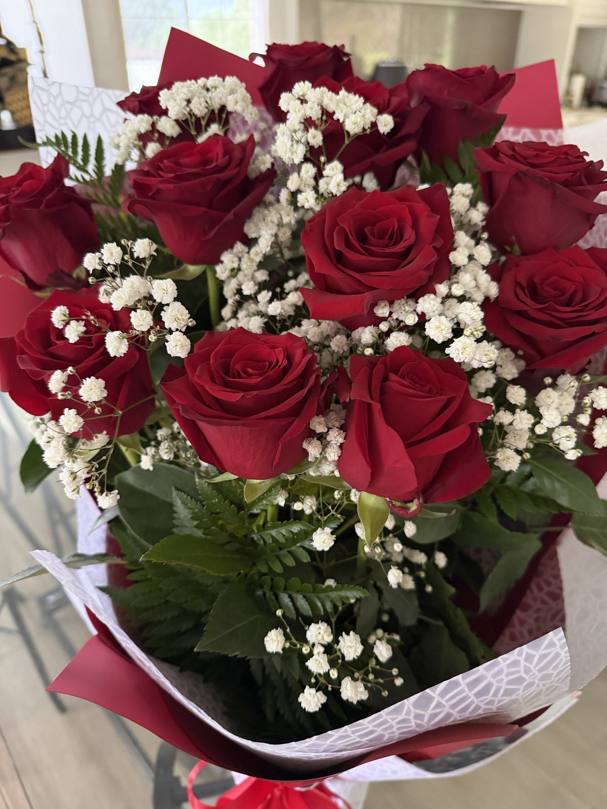 赤いバラ12本と白いかすみ草を赤いラッピングでまとめたプロポーズ用の花束
