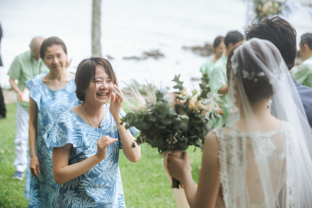 ブーケを持つ花嫁に笑顔で声をかける水色の衣装のご家族
